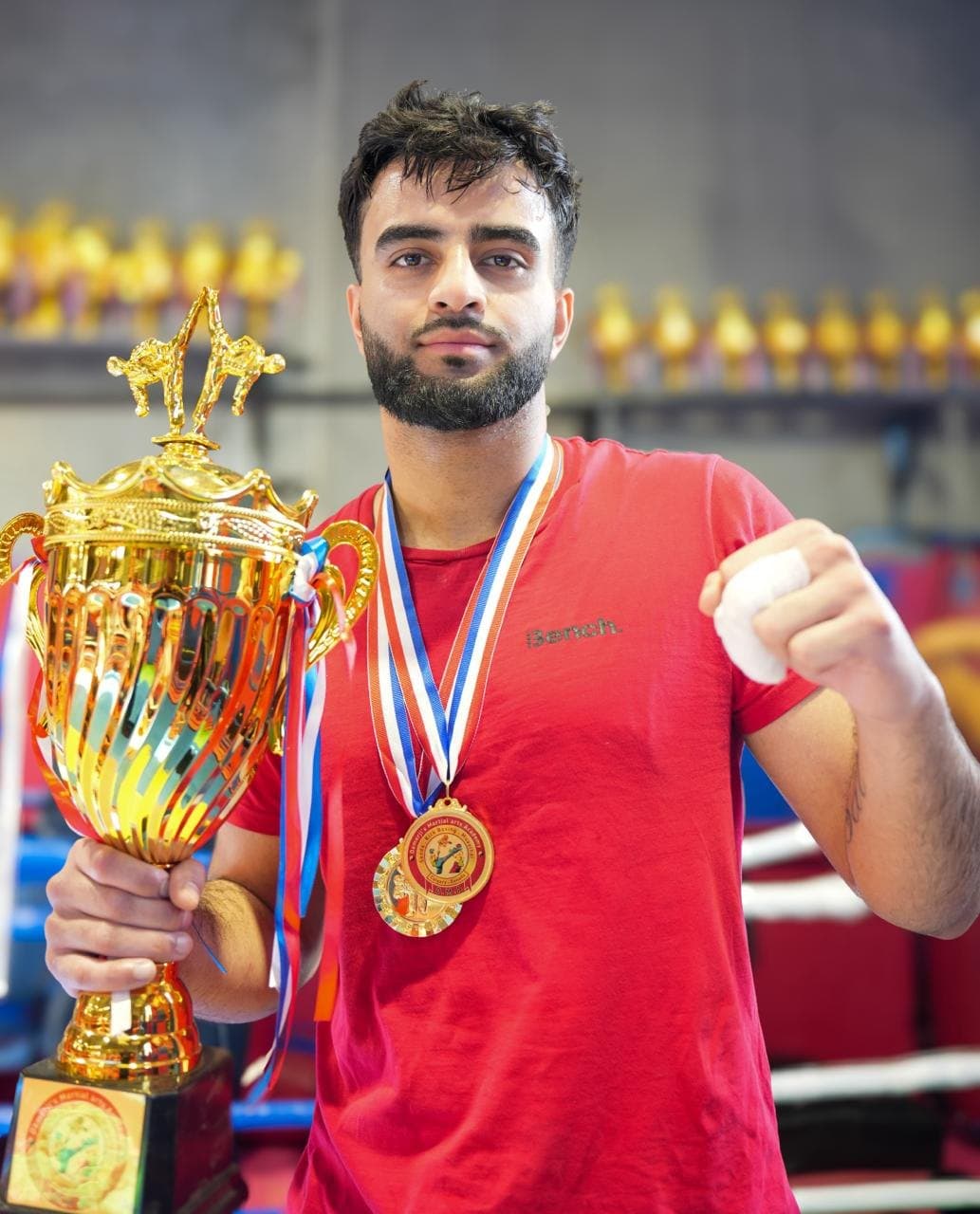 Adult DMA athlete with championship trophy and medals, hands wrapped